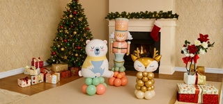 Festive balloon stacks from the Christmas Balloon Shop in a holiday setting with tree and fireplace.