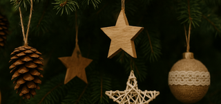 Woodland & natural Christmas decorations with pinecone, wooden stars, and rustic bauble hanging on a tree branch.