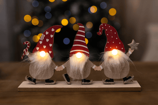 Christmas LED Gonk Decoration Set of 3 with glowing noses and festive hats against a warm, bokeh-lit background