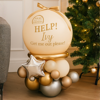 Butter Gold & Silver Elf Pop Me Balloon next to a Christmas tree, featuring elegant butter, gold, and silver balloons.