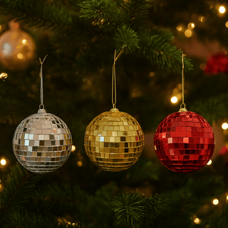 Gold, silver, and red disco mirror christmas tree baubles hanging on a tree, reflecting light and adding sparkle to festive decor.
