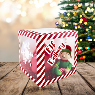 Elf Delivery Gift Box with candy cane stripe design displayed on wooden table, featuring festive decorations, perfect for Christmas surprises.